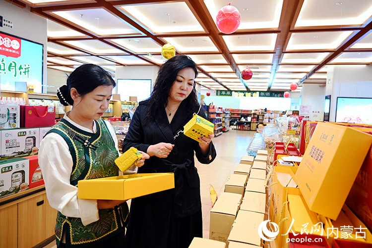 马慧平(右)和店员正在理货。人民网记者 刘艺琳摄